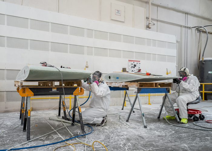 Boat parts being sanded by two employees