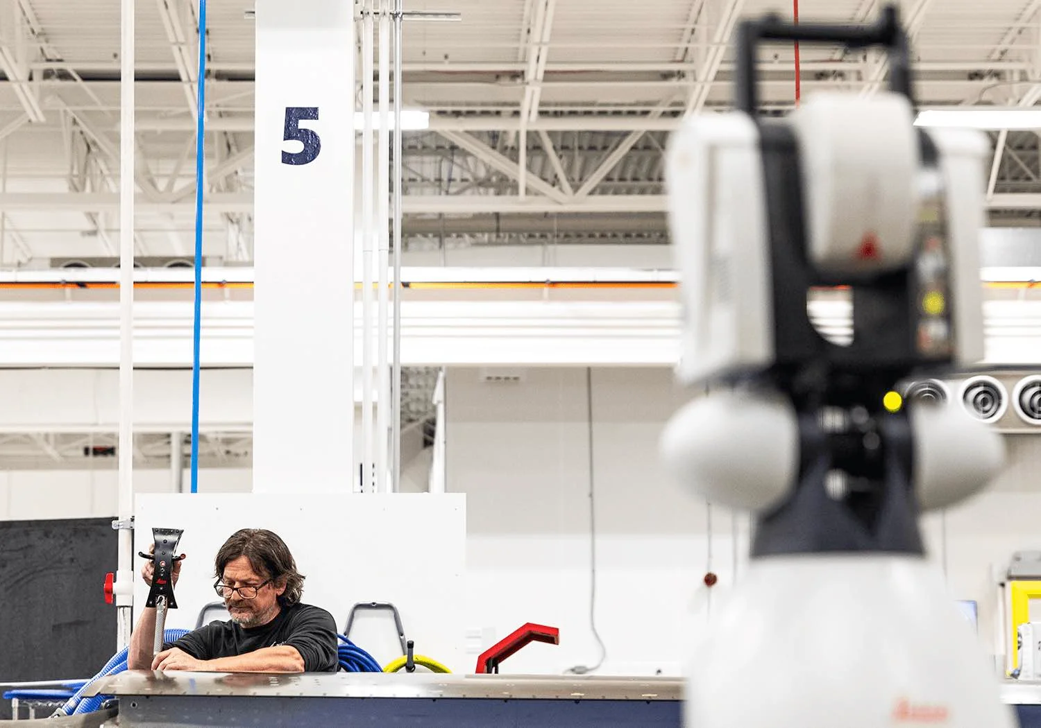 A man uses a laser tracker on a composite part