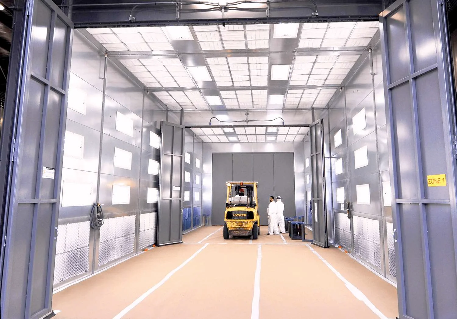 Paint booth with forklift and employees inside